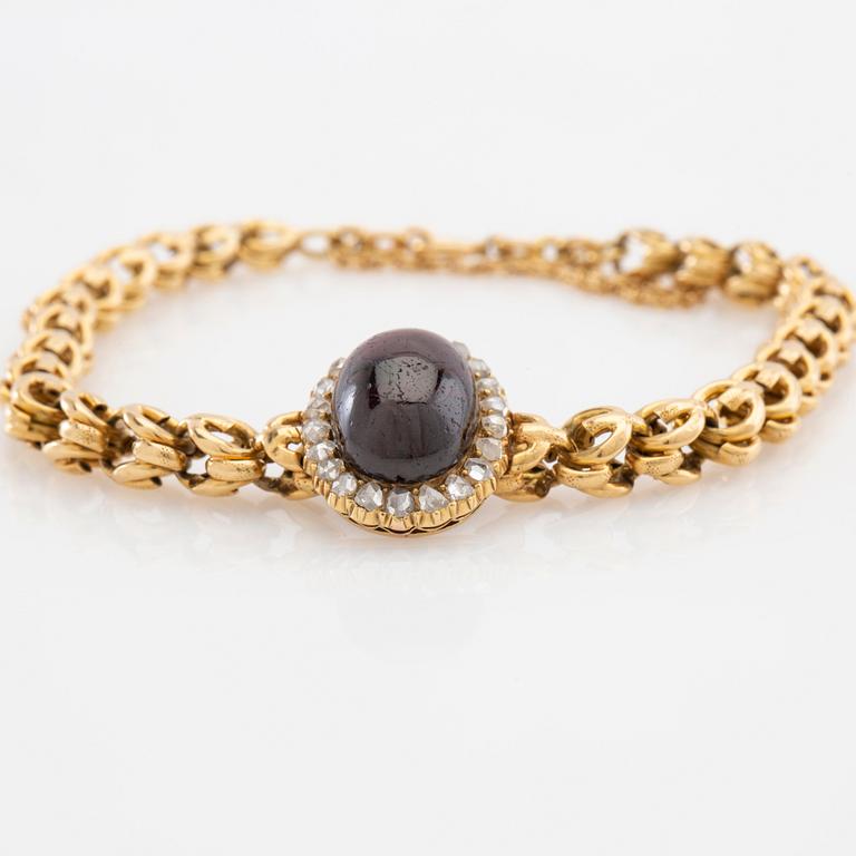 Bracelet in 18K gold set with rose-cut diamonds and an oval cabochon-cut garnet.