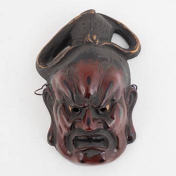 A Japanese lacquered wooden mask, 20th century. Signed.