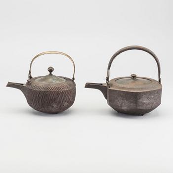 A set of two Japanese early 20th century cast iron chōshi (銚子).