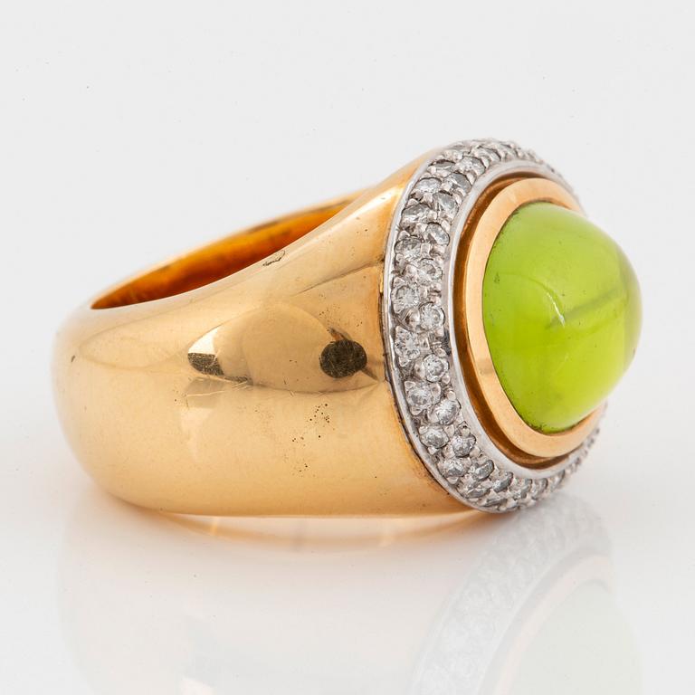 An 18K gold Steinlin ring set with a cabochon-cut peridot and round brilliant-cut diamonds.