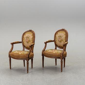 A pair of Louis XVI-style walnut armchairs circa 1900.