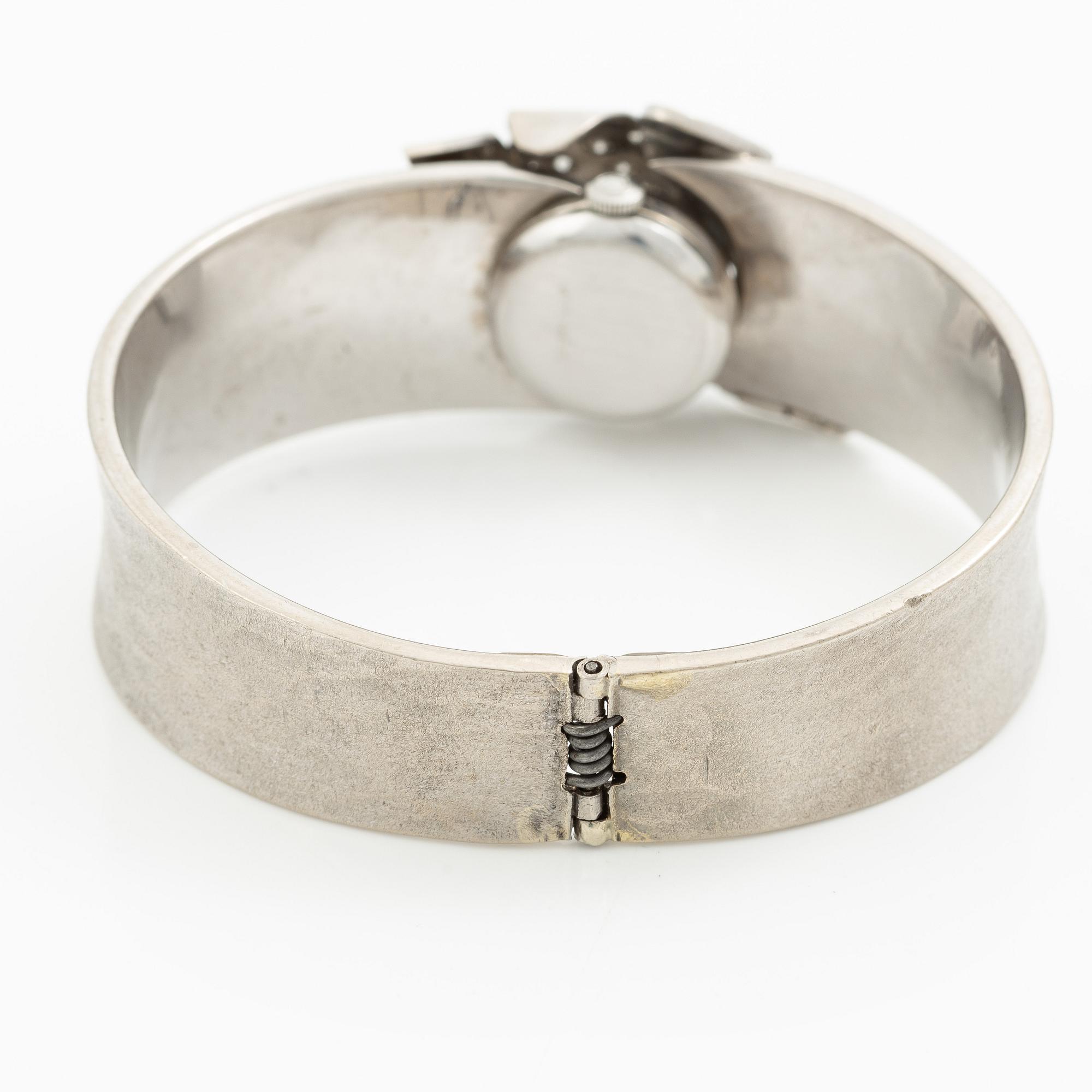 Aftonklocka/armring, Bo Dolk, 18K vitguld med briljantslipade diamanter, 1970-tal.