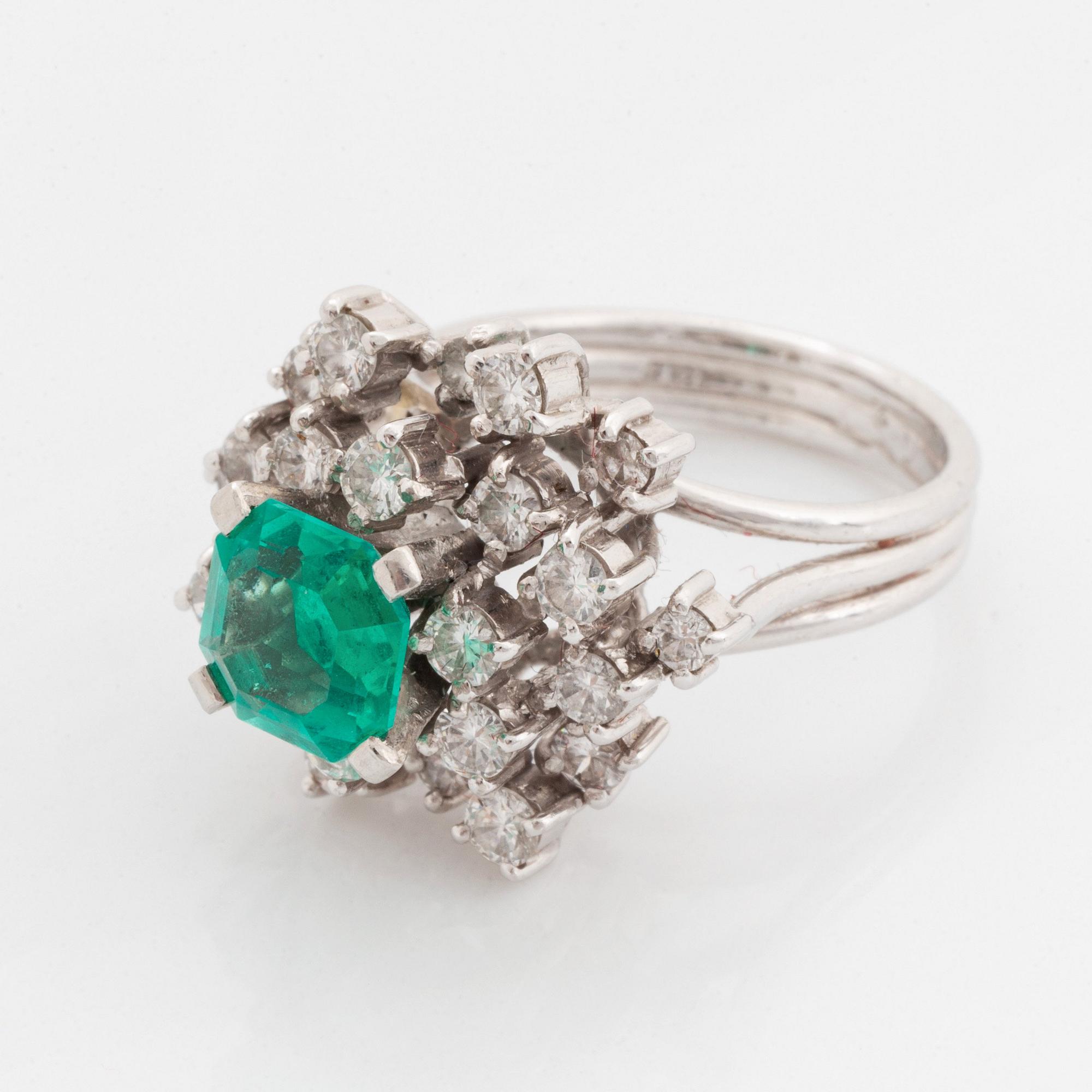 Ring platina med en fasettslipad smaragd och runda briljantslipade diamanter.