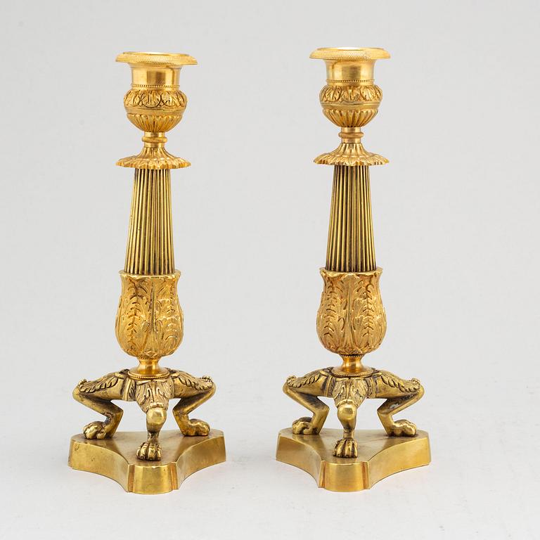 a pair of empire-style brass candlesticks from around 1900.