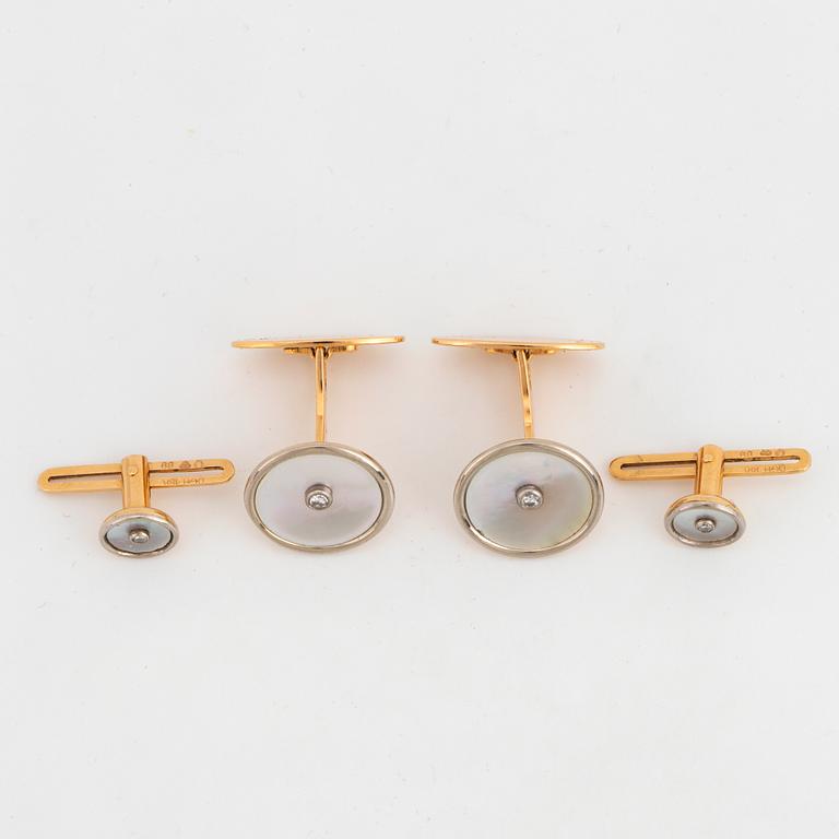 A pair of cufflinks and a pair of shirt buttons.