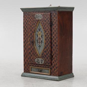 A painted wall cabinet, dated 1817.