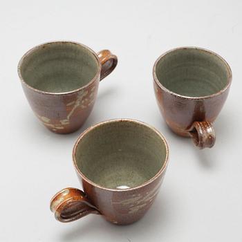 A tea pot and three tea cups in saltglazed stoneware by Christer Sjöblom, signed tea pot.