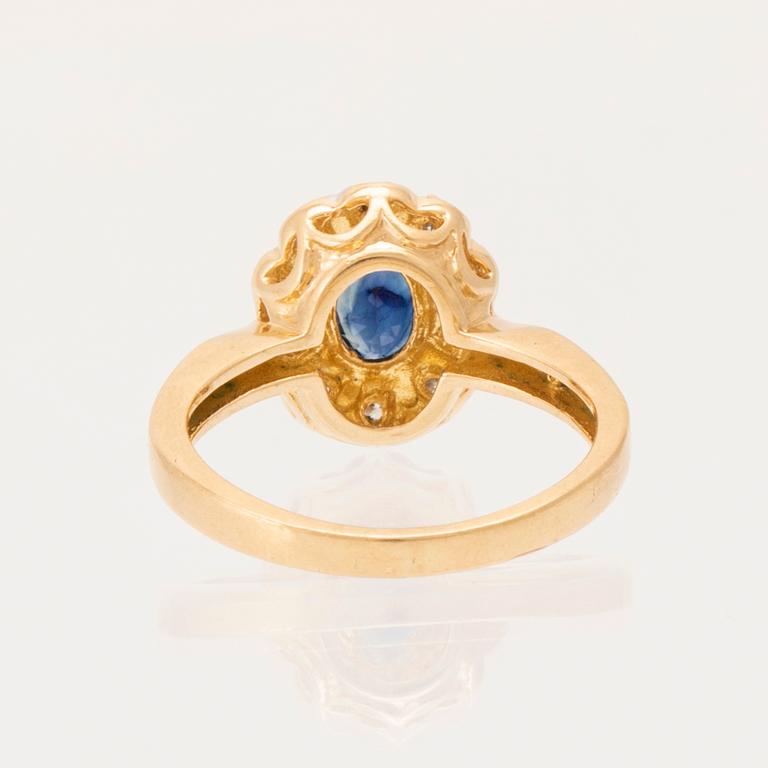 An 18K gold ring set with an oval faceted sapphire and round brilliant-cut diamonds.