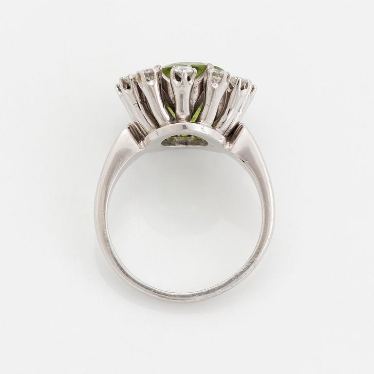 An 18K white gold ring set with a faceted peridot and round brilliant-cut diamonds.