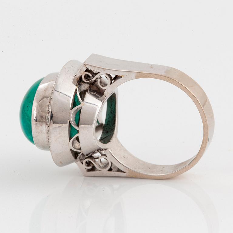 An 18K white gold ring set with a cabochon-cut emerald and round brilliant-cut diamonds.