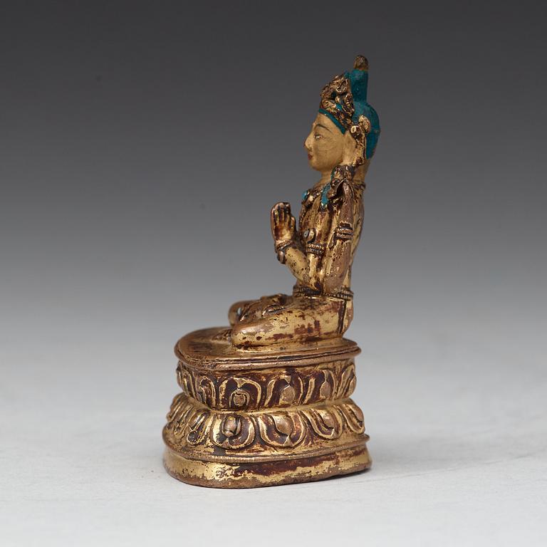 A gilt copper alloy four armed Tibetan figure of Shadakshari Lokeshvara, 16th Century or earlier.