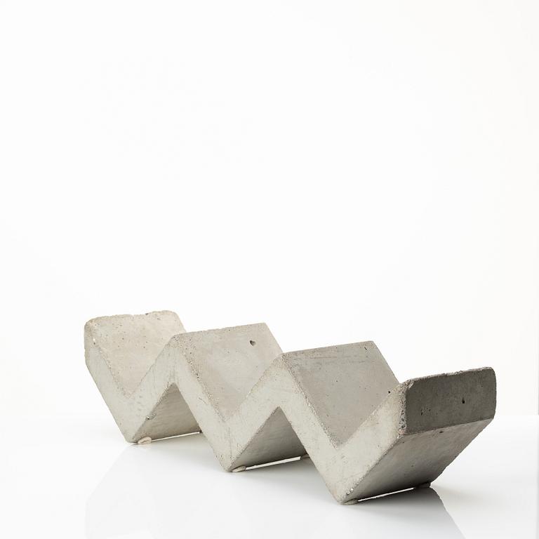 A mixed lot comprising a pair of limestone bookends, a bookshelf and two plates in concrete.