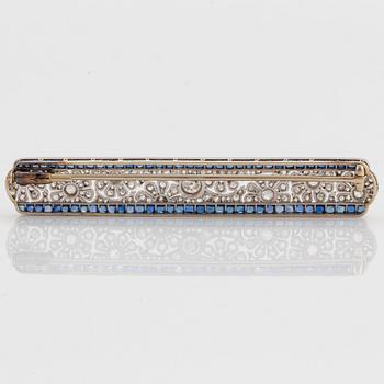 A platinum and gold brooch set with old- and rose-cut diamonds and faceted sapphires.