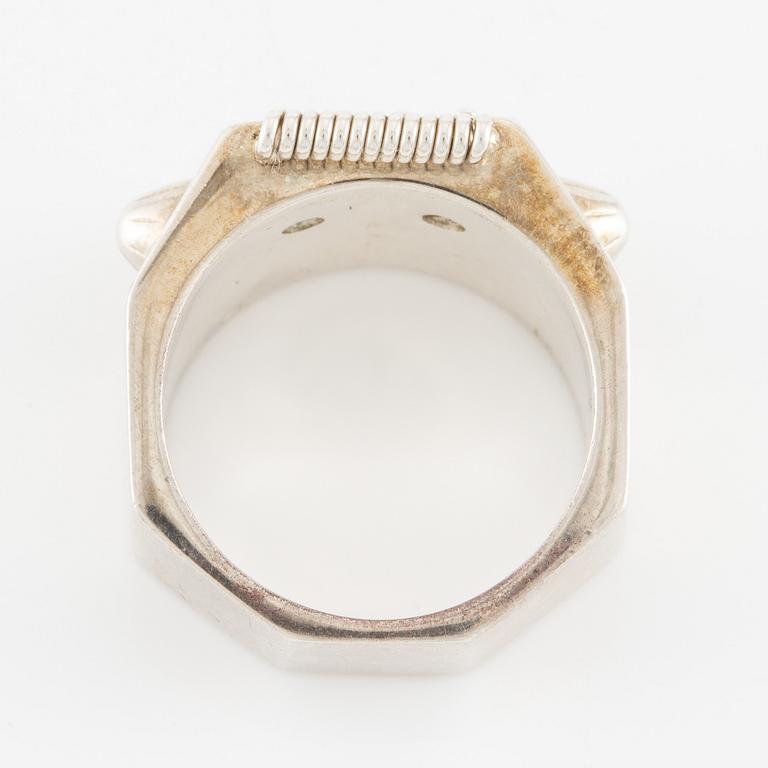 Maria Nilsdotter ring i form av ett robothuvud, sterlingsilver och gröna ögon.