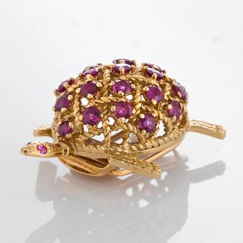 A Cartier turtle brooch in 18K gold set with rubies.