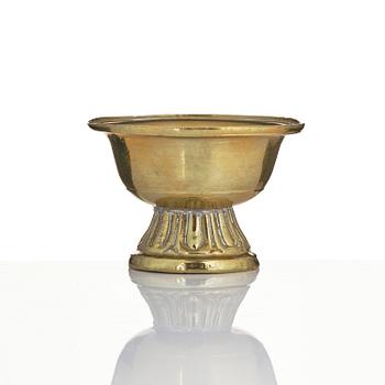 A bronze deity and a brass sacrificial bowl, Tibet, circa 1900.