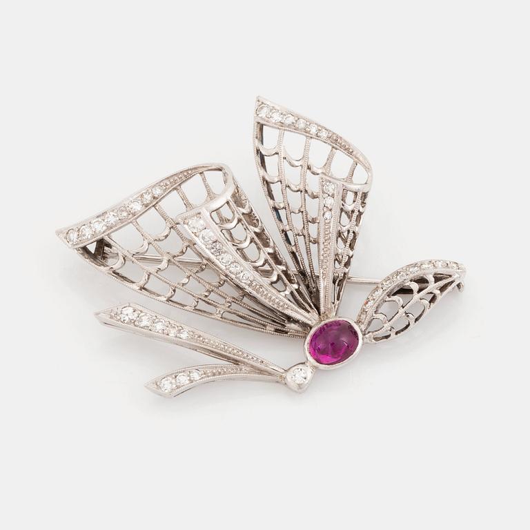 An 18K white gold brooch set with a cabochon-cut ruby and eight-cut diamonds.