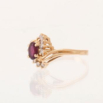 A 14K gold ring set with an oval faceted synthetic ruby and round brilliant-cut diamonds.