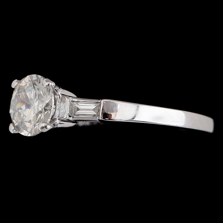 RING, 18 k vitguld, solitär briljantslipad diamant ca 1.00 ct, 2 baguetteslipade diamanter tot ca 0.16 ct.
