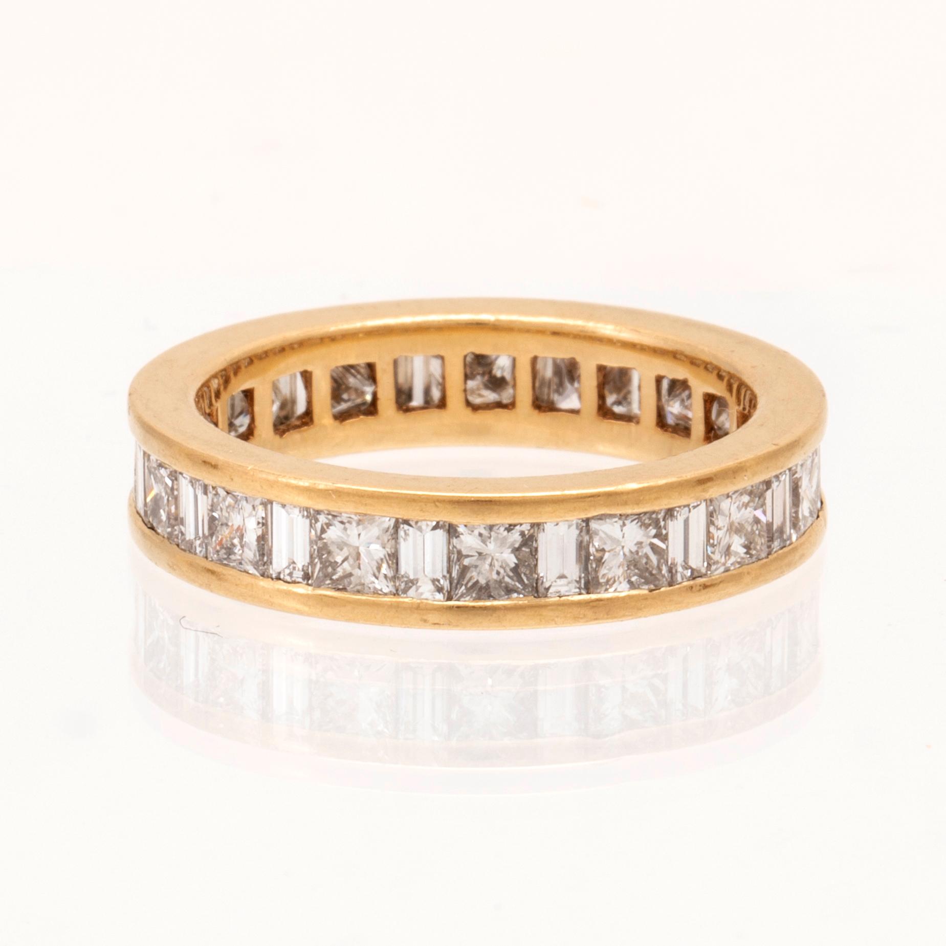 An 18K gold eternity ring set with baguette and princess cut diamonds by Hartmann's Denmark.
