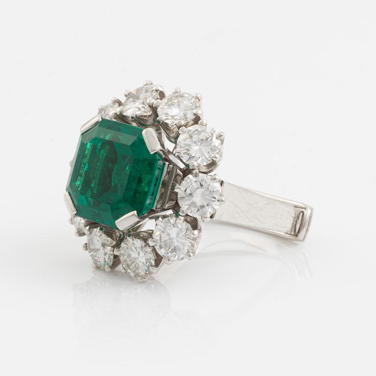 A WA Bolin platinum ring set with a step-cut emerald and round brilliant-cut diamonds.