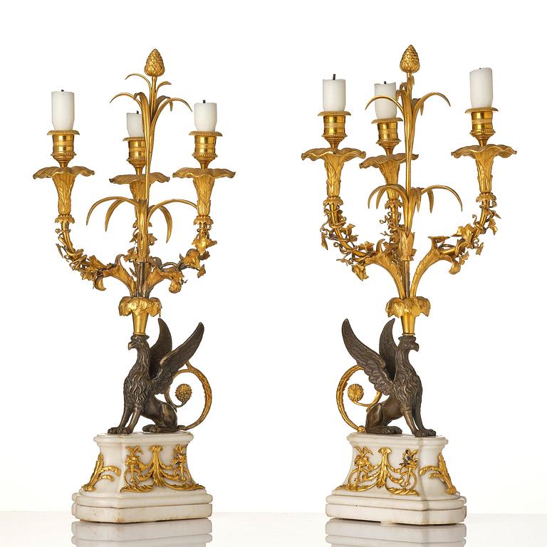 A pair of three-light Louis XVI patinated and ormolu candelabra in the manner of François Rémond, late 18th century.