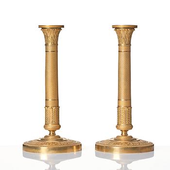 A pair of French Empire ormolu candlesticks, early 19th century.