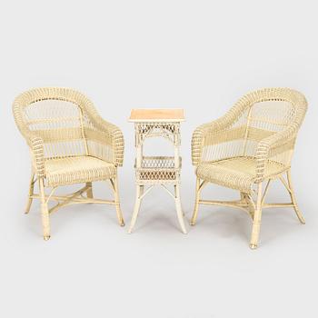 A mid-20th-century three-piece rattan furniture set including two armchairs, and a table.