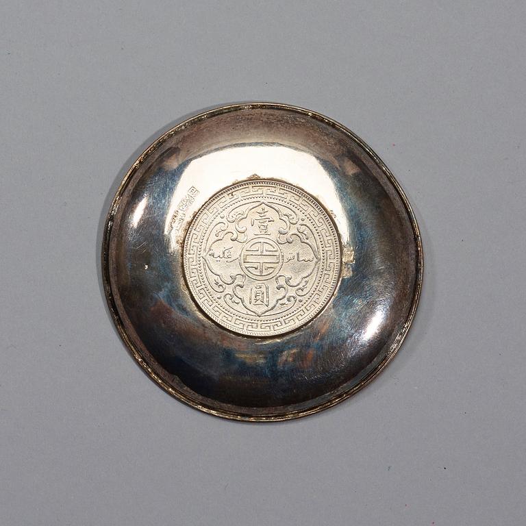 A small silver plate with a One Dollar coin, Qing Dynasty, Guangxu 1899.
