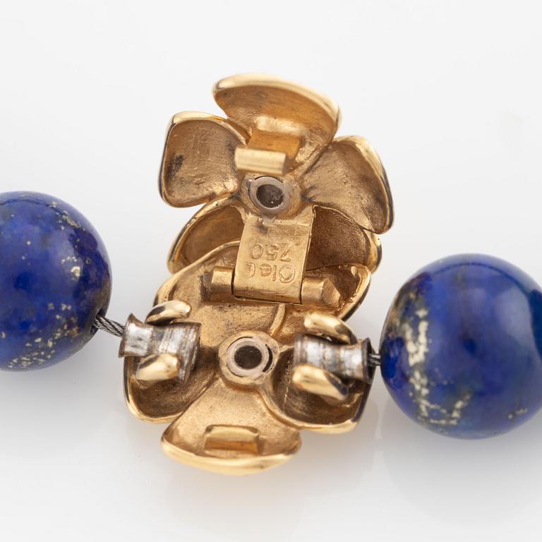 An Ole Lynggaard clasp in 18K gold with round brilliant-cut diamonds and a lapis lazuli necklace.