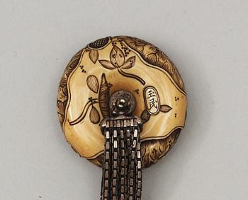 A Japanese embroided tabakoire with a kanamono in the shape of two tigers, a metal chain that holds a carved ivory manjû, second half of 19th Century. Signed.