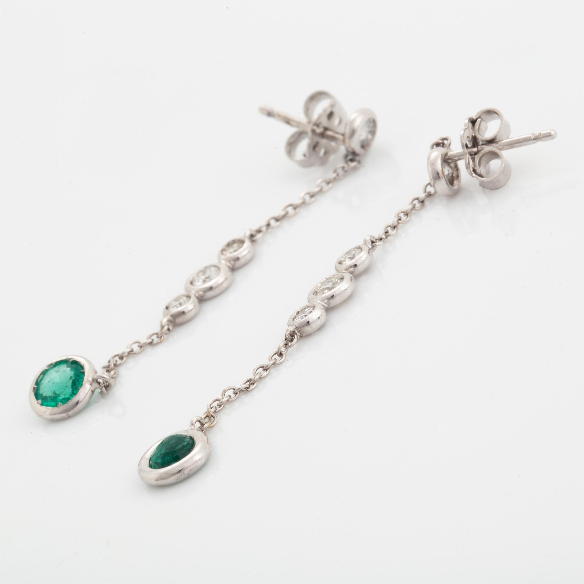 A pair of 18K white gold earrings set with faceted emeralds.