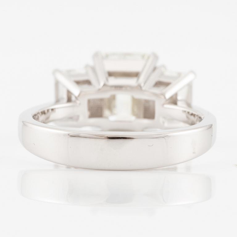 An 18K white gold ring set with three emerald-cut diamonds.