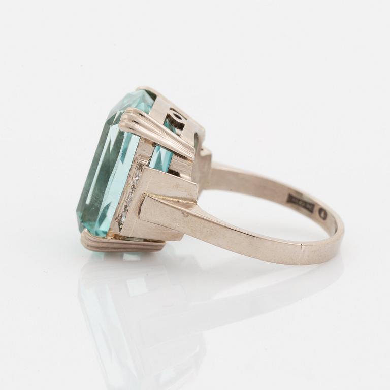 An 18K white gold ring set with a faceted aquamarine and round brilliant-cut diamonds.