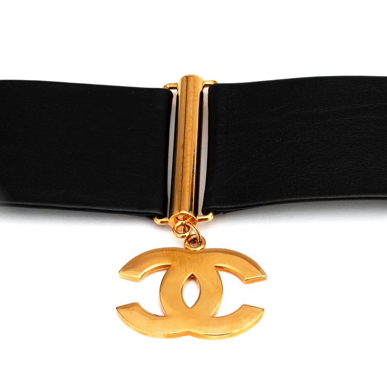 CHANEL, a black leather belt with golden logo charms.