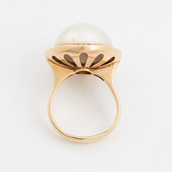 A 14 k gold ring set with a half pearl and round brilliant-cut diamonds.
