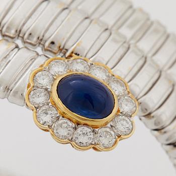 An 18K gold bangle set with cabochon-cut sapphires and round brilliant-cut diamonds.