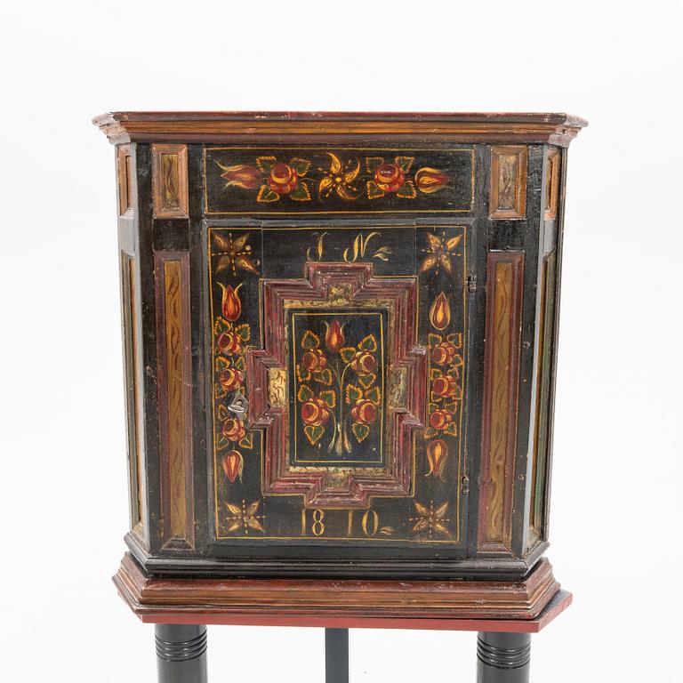 Corner cabinet on a legged stand dated 1810.