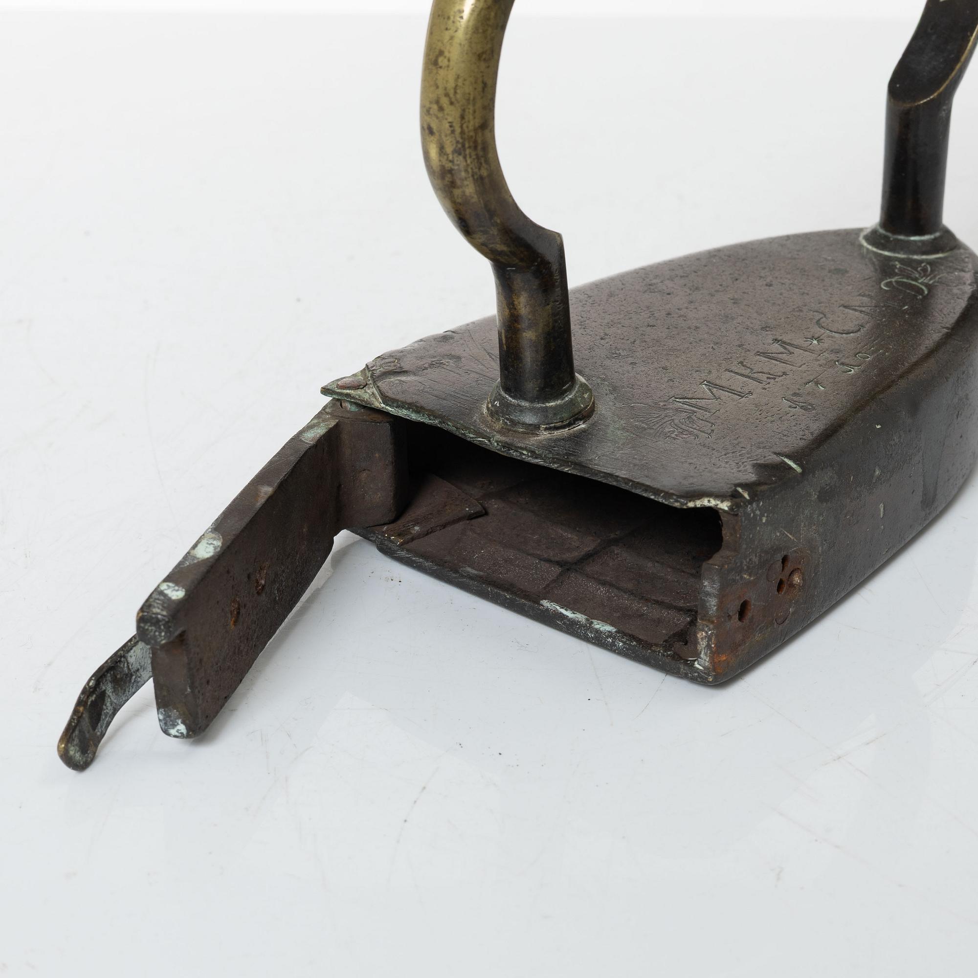A brass clothes iron, dated 1710.