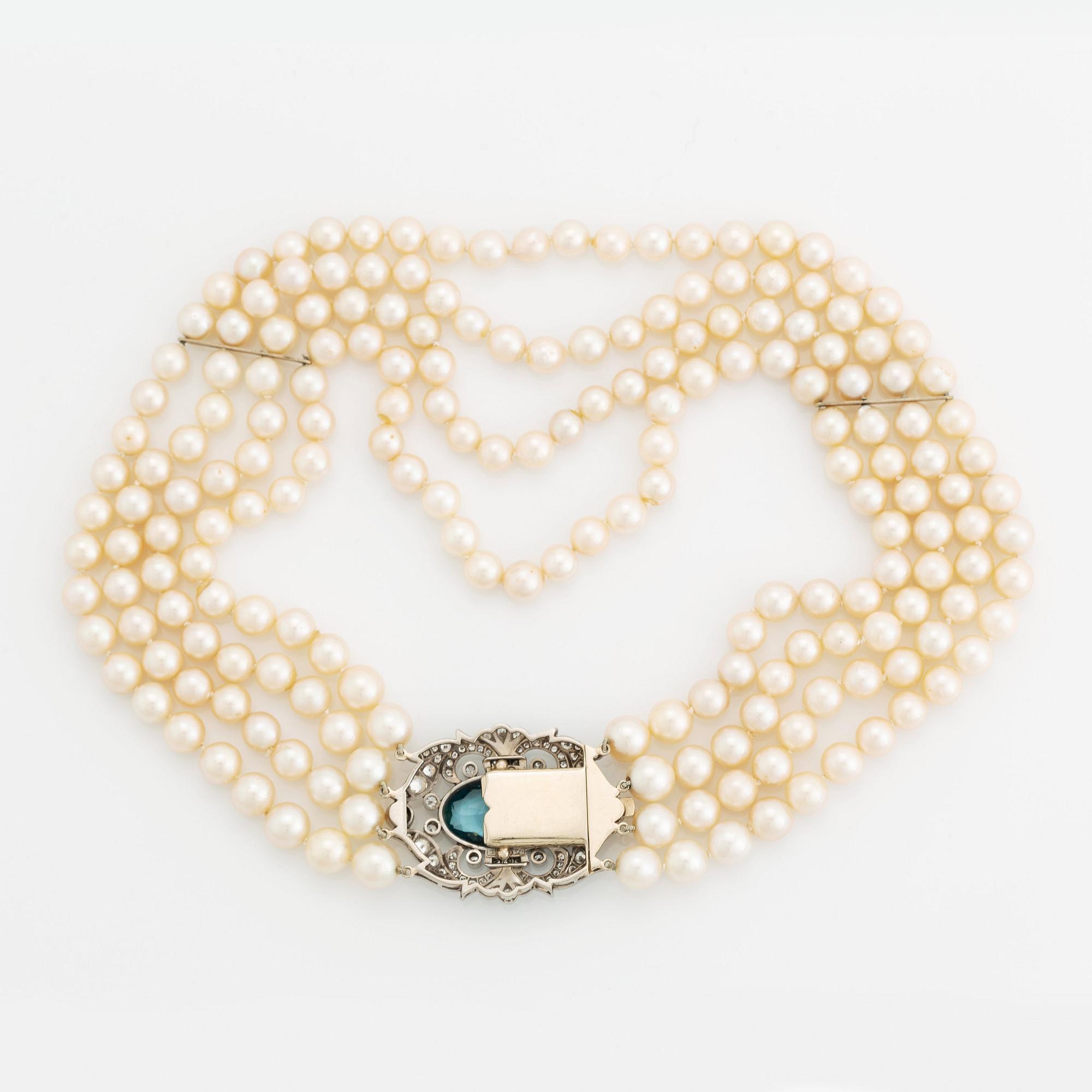 A four strand cultured pearl necklace with a clasp in 14K gold set with a faceted aquamarine.