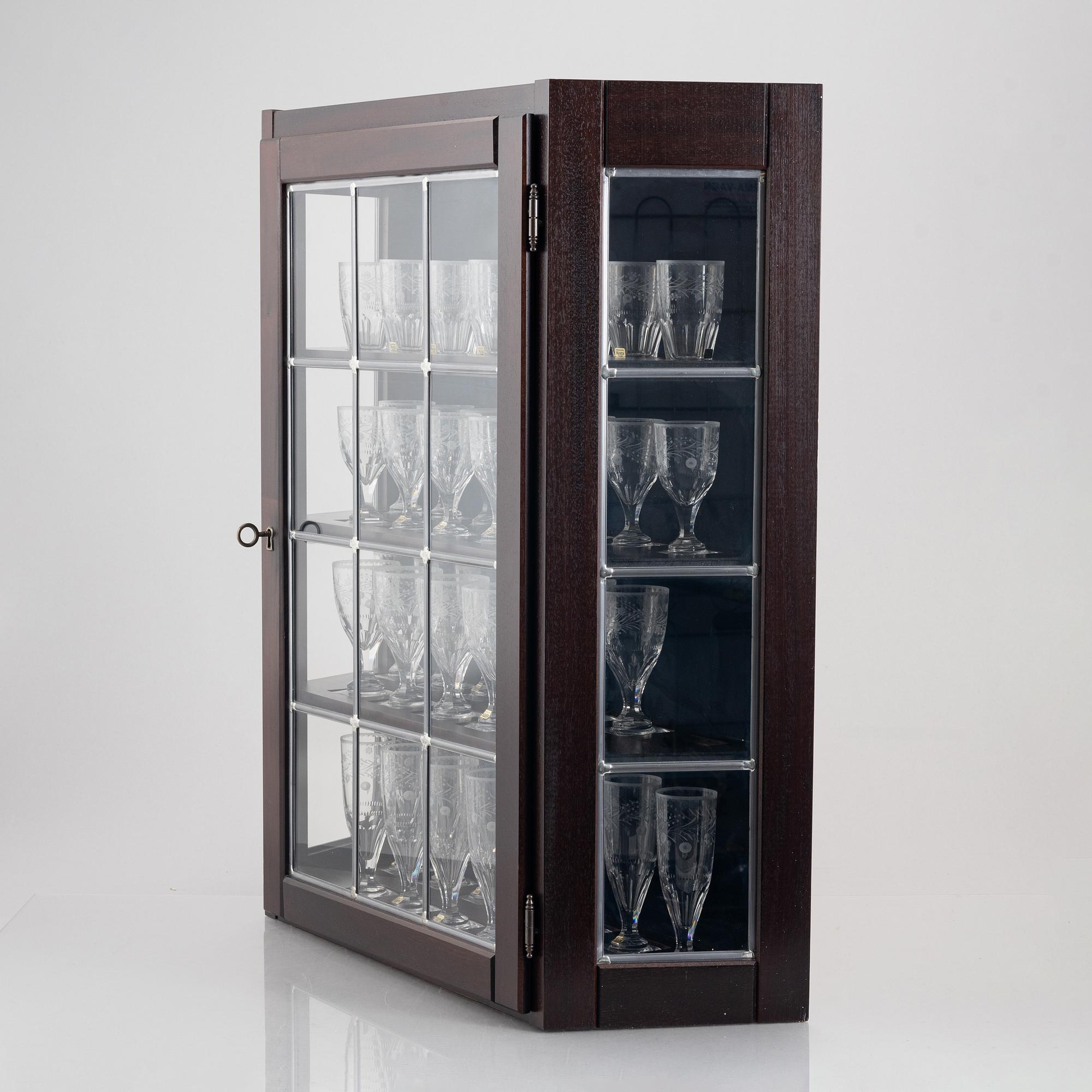 A display cabinet with a 47-piece glass service, "Koskull" from Kosta, Sweden.