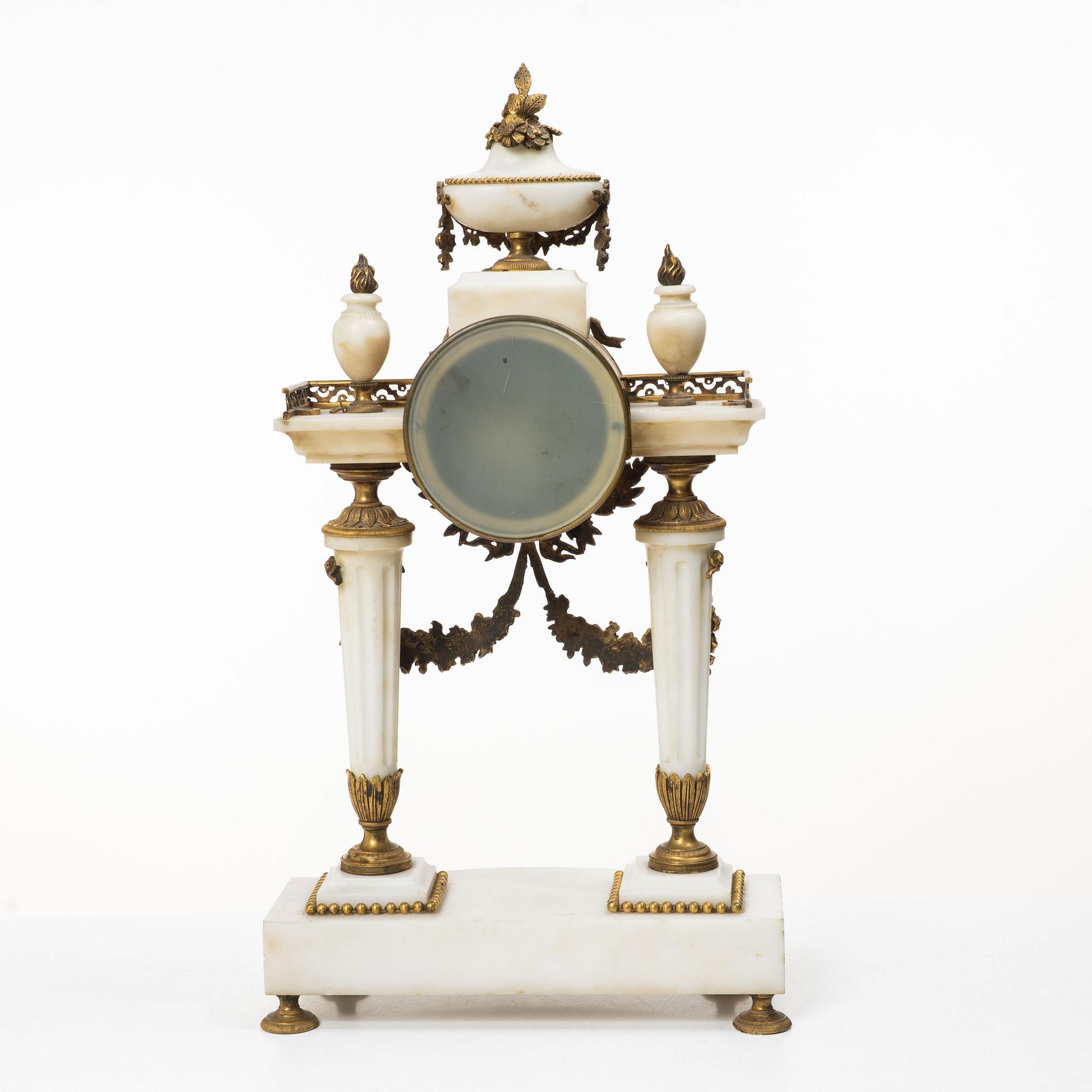 A Louis XVI-style mantle clock and a pair of candelabras. Early 20th century.