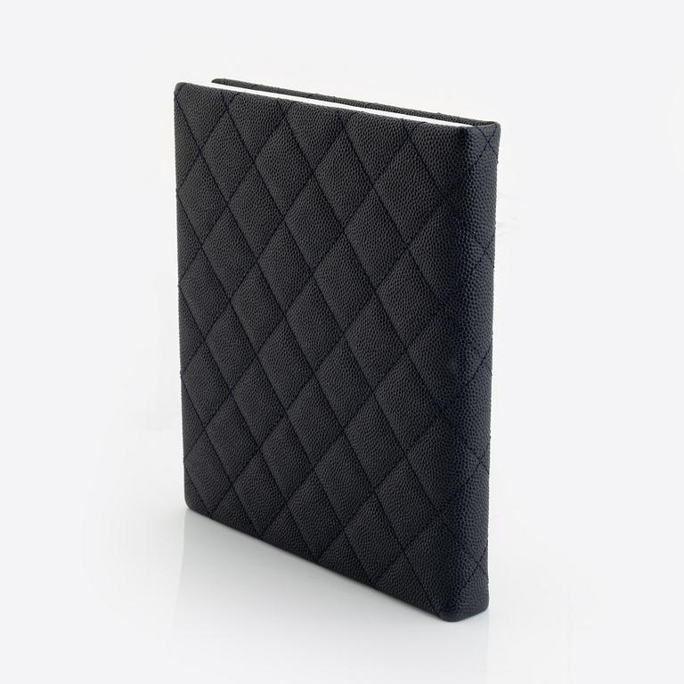 Chanel, a dark blue navy caviar leather notebook.