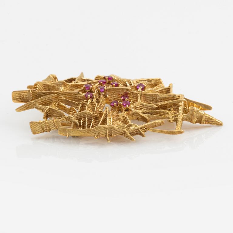 An 18K gold brooch set with faceted rubies.
