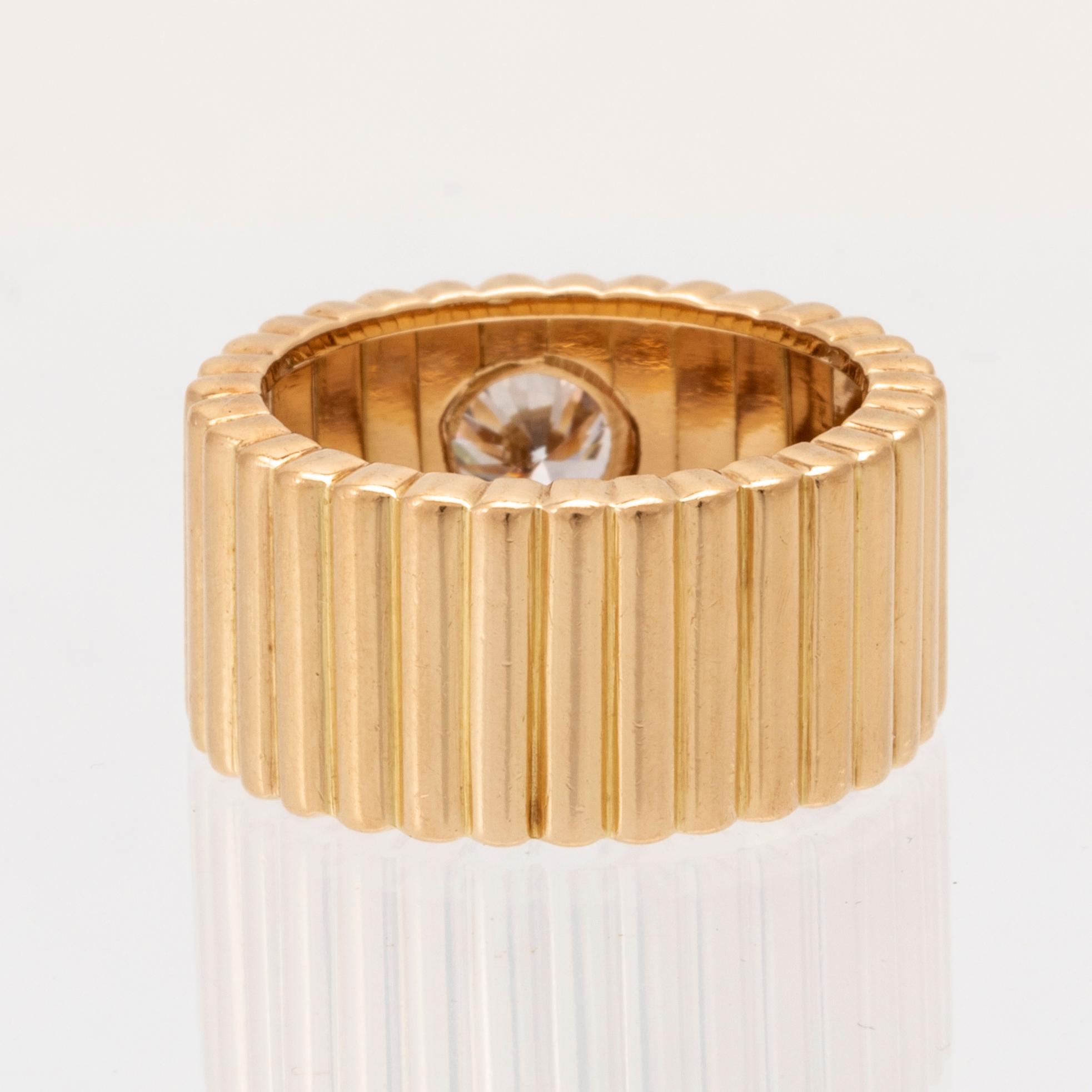 An 18K gold solitaire ring with a round brilliant-cut diamond.