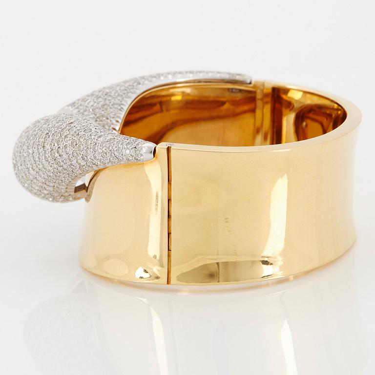 An 18K gold bangle set with round brilliant-cut diamonds.