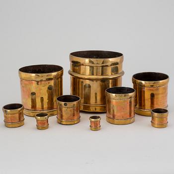 A set of nine brass measures, The Oriental Metal Pressing Works, Ltd, Bombay, Indien, 20th Century.