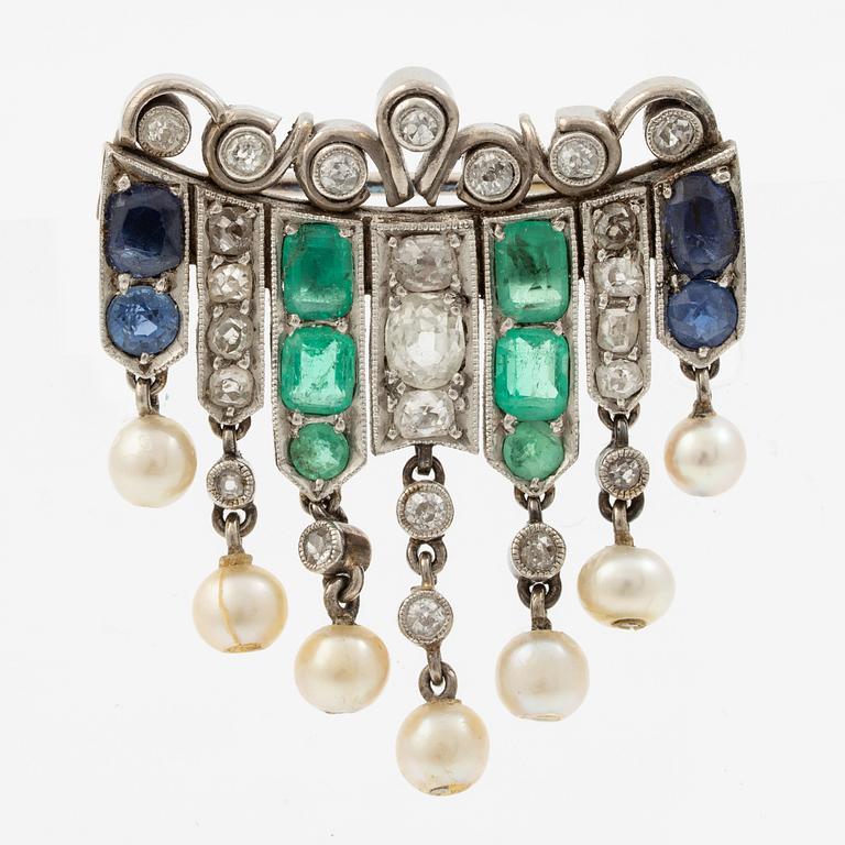 Brooch in platinum set with old-cut diamonds, sapphires, emeralds, and pearls.