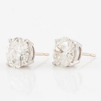 A pair of earrings in 18K white gold set with two round brilliant-cut diamonds.