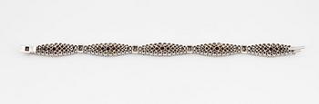 An 18K white gold bracelet set with rubies and round brilliant-cut diamonds.